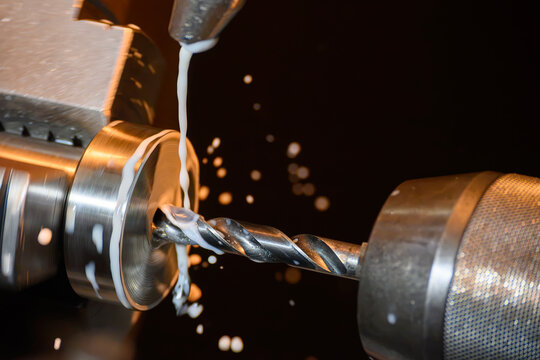 High-precision lathe machine performing a hole making process on a ring shape part with liquid coolant.
