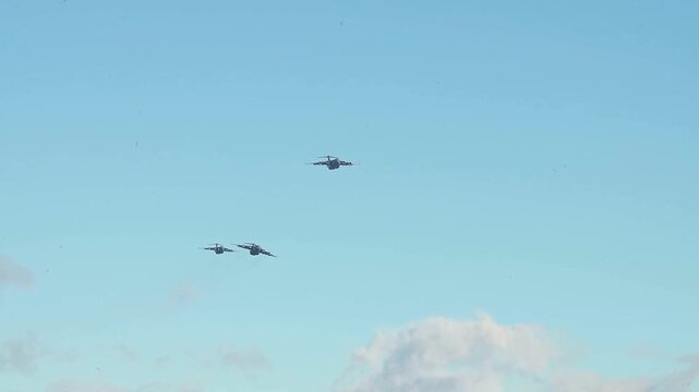 Three Military Transport Aircraft Flying in Tactical Formation Across Clear Blue Sky During Coordinated Air Force Training Exercise.
