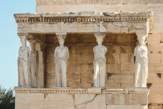 Elegant marble Caryatids of the Erechtheion temple at the Acropolis in Athens, Greece, showcasing ancient Greek architecture and artistry under clear daylight.