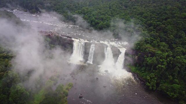Aerial drone view of Athirappilly Waterfalls cascading through lush tropical rainforest during monsoon in Kerala, India