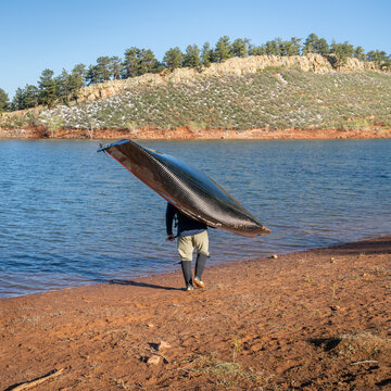 senior paddler is launching his decked touring canoe on shore of Horsetooth Reservoir - early spring scenery of Colorado foothills