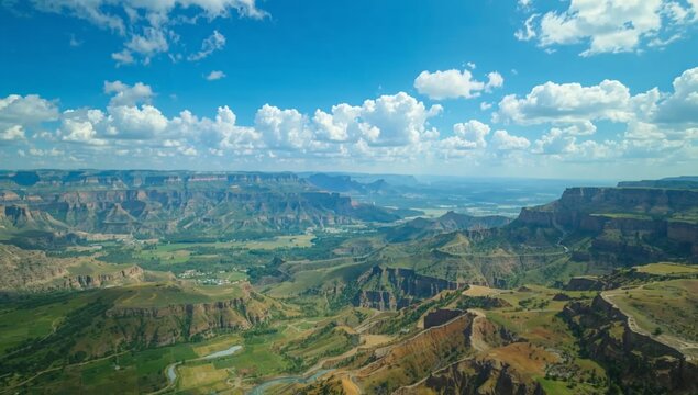 Panoramic aerial view of a vast canyon landscape under a bright blue sky.