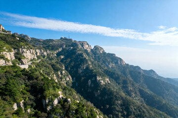 Obraz premium A panoramic view of rugged mountain ranges covered in green vegetation under a clear blue sky