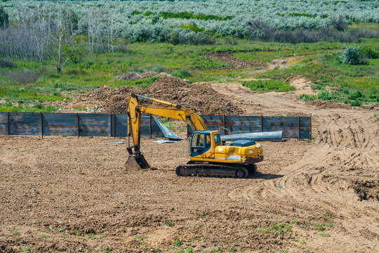 A yellow excavator is working at a construction site