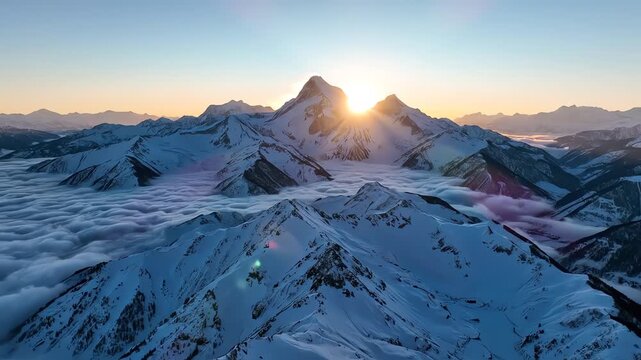 Sunrise over snow covered mountain peaks with sea of clouds