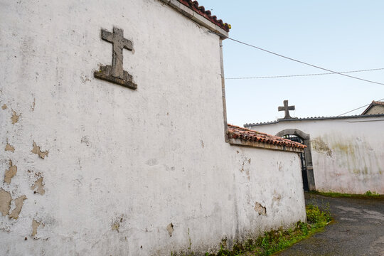 Traditional stone crosses on the weathered white walls of a rural cemetery along the historic Camino Primitivo route in Asturias, Spain