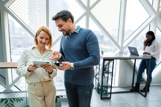 Business colleagues discussing data on digital tablet and smartphone in modern office