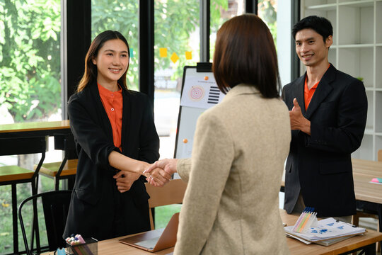 Business professionals shaking hands during a team meeting in a modern office workspace