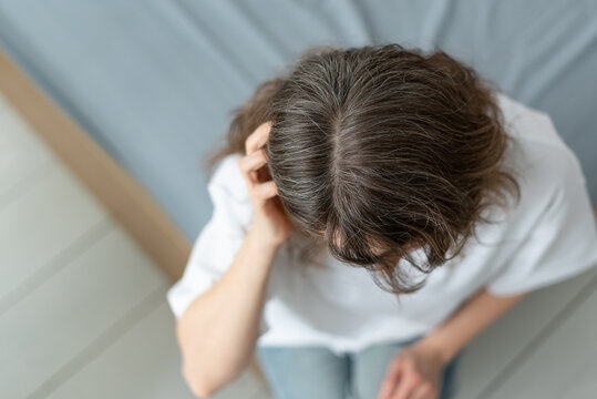 A woman estimates how much of her hair has turned gray already. The mature adult calculates percentage of silver strands compared to natural color. Mother measures her aging progression.