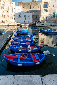 Monopoli, Italy - March 9, 2025: Ancient port (Porto antico) with moored blue boats. 15th century Gate of the ancient port leads from the city to the harbor