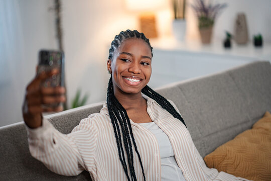 Young black woman taking selfie with smartphone at home