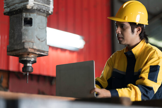 Manufacturing industry and factories. Heavy industry machine. Maintenance or repair industrial machine. Asian male factory engineer inspecting or maintenance vertical drilling machine in factory
