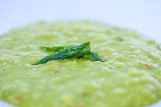 Close‑up of creamy asparagus risotto garnished with fresh asparagus tips, highlighting smooth texture and vibrant green color in a minimalist gourmet presentation.