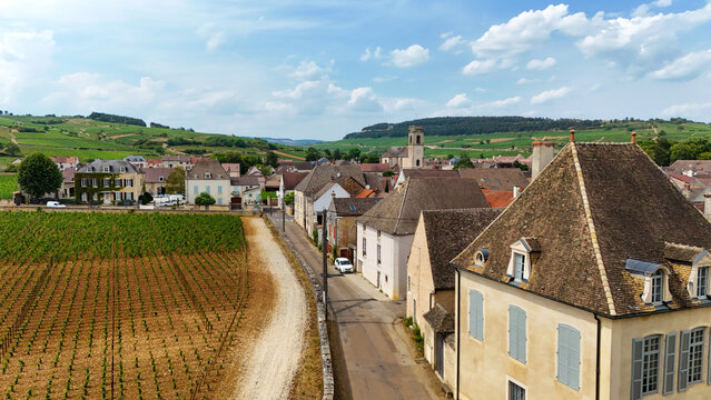 Aerial view of Pommard village in Burgundy, France, surrounded by lush chardonnay and pinot vineyards under a bright summer sky, capturing rural wine‑country charm.