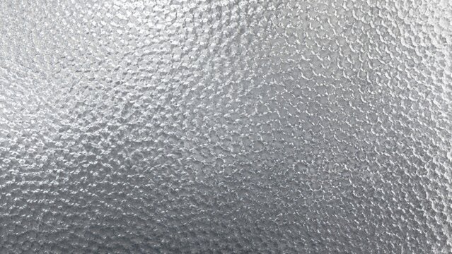 Close-up textured metallic silver surface with dimpled hammered pattern and reflective highlights