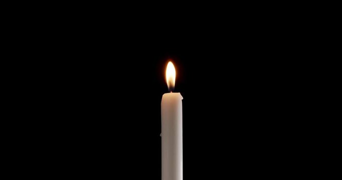 Moody candle on a black background. Watch how the flame of the candle slowly flickers. This glowing candle is ideal for background or over-layer with blending mode add, screen, lighten.