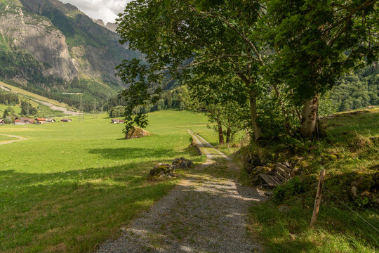 Guttannen, Switzerland. Gravel hiking trail with wooden bench and alpine valley in the Bernese Oberland
