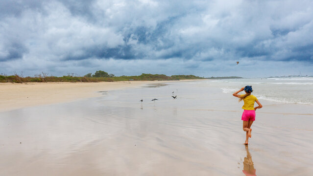 Girl running on beach with birds, Galapagos