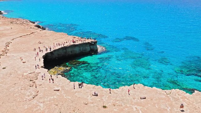 Drone view of Cape Cavo Greco coastline in Cyprus. Natural cave openings, clear blue sea and rugged limestone rocks form a dramatic coastal scene.