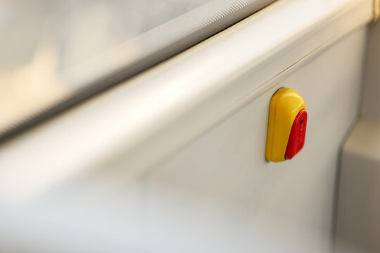 Red and yellow stop request button installed on interior panel near window in public transport vehicle for passenger request signal concepts.
