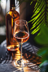 Obraz premium Blush rose wine glass standing on dark tabletop. Exotic resort lounge bar atmosphere and premium hotel catering hospitality concept.