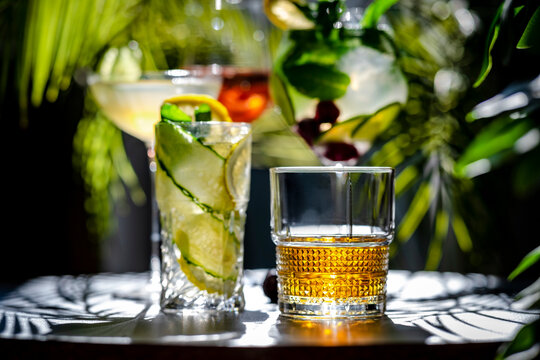 Refreshing alcoholic cocktail drinks served in assorted elegant glassware. Sophisticated bar menu and summer evening party mood concept.