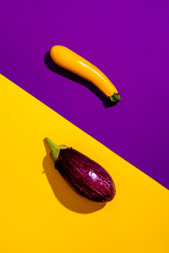 Yellow zucchini and purple eggplant for contrast food art. Modern culinary still life concept on a colorful background.