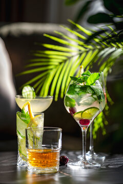 Diverse alcoholic cocktail drinks with fresh herbs served in crystal glassware. Premium resort hospitality and relaxing summer evening concept.