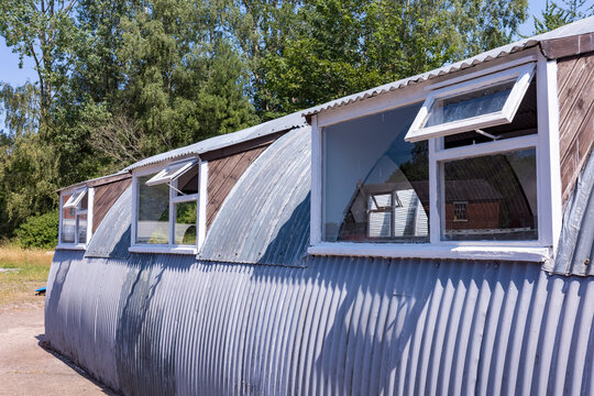 Nissan hut exterior showcasing corrugated iron construction and white dormer windows against a backdrop of green trees, symbolizing military history and temporary housing solutions