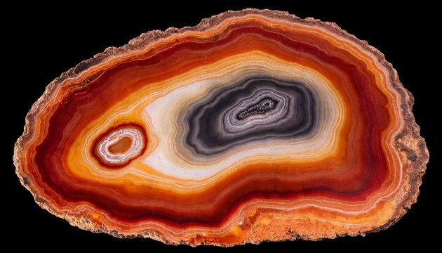 A polished cross section of a colorful agate gemstone with concentric bands of orange, red, white, and black colors against a dark background