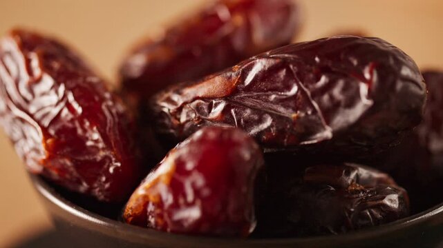 Sweet dried dates in a bowl. Glossy medjool dates texture with soft warm lighting for healthy eating and natural sweetener design.
