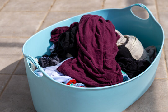 lue laundry basket filled with dirty clothes ready for washing on tiled floor