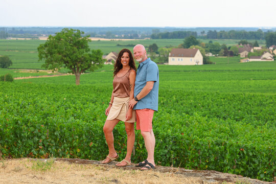 Couple standing beside vineyards in Burgundy, France, overlooking rolling countryside and wine-growing landscapes in one of the world's most celebrated wine regions.