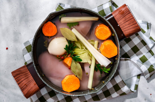 Cooking homemade chicken broth process. Fresh raw fillet in water with vegetables and spices.