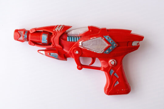 Red vintage plastic toy ray gun with sci-fi design isolated on white background. Space blaster toy pistol for children play, gaming, and leisure activity.
