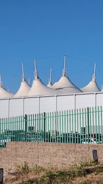 Bognor Regis West Sussex England UK. 14.07.2026. Video. A row of futuristic white tensile structures with pointed peaks stands under a bright blue sky