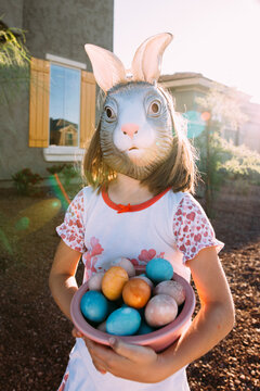 little girl in easter bunny mask with eggs