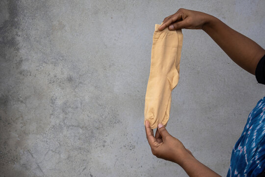 Two hands holding a pair of straight skin color socks outdoor. Premium stretchable nylon thin hosiery for women lifestyle clothing. Comfortable breathable elastic cotton texture.