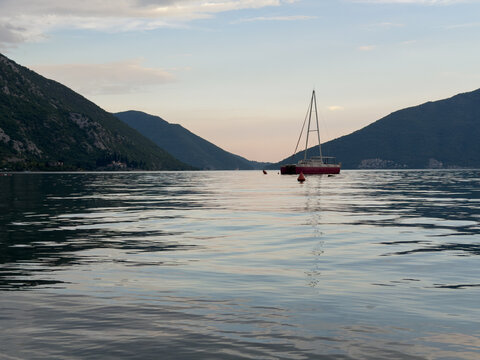 Solitary sailing yacht at sunset in the Bay of Kotor, Montenegro, Adriatic Sea, peaceful Mediterranean seascape