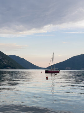 Solitary sailing yacht at sunset in the Bay of Kotor, Montenegro, Adriatic Sea, peaceful Mediterranean seascape