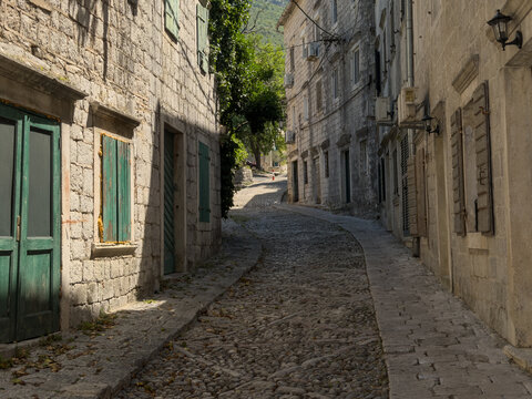 Narrow historic street with traditional stone houses on a sunny summer day, charming old town European architecture and travel destination