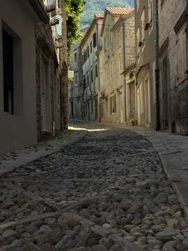 Narrow historic street with traditional stone houses on a sunny summer day, charming old town European architecture and travel destination