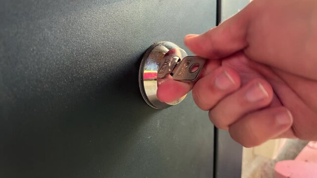 Close-up of a man's hand turning a key to unlock a door, home entry, residential security, access control, property protection.