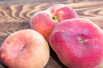 Flat Saturn donut peaches lying on a rustic wooden table surface, close up shot. © ALEKSFILM
