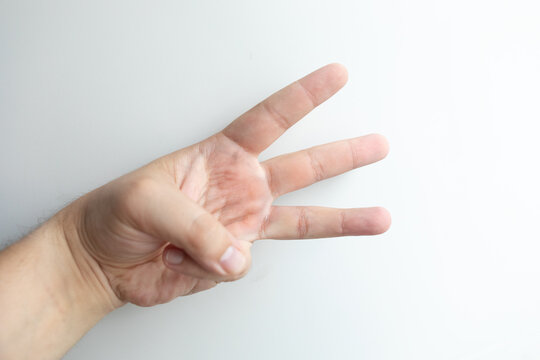 Human hand showing three raised fingers against a clean white background, representing number three, counting, numerical communication, education and a simple visual concept image