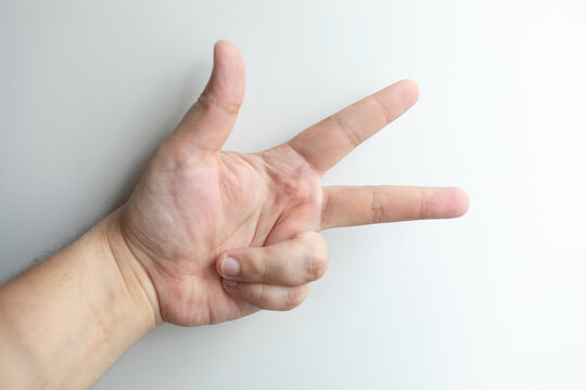 Close-up of a human hand showing three raised fingers against a clean white background, representing number three, counting, communication, education and a simple visual symbolism