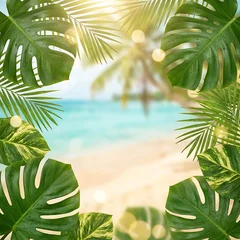 Tropical beach scene framed by lush green monstera and palm leaves with ocean view sand © Doley Design