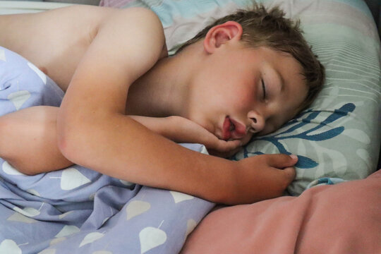 A nine-year-old boy sleeps soundly, his hand under his cheek