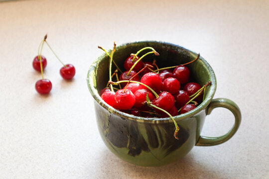 A close-up of ripe cherries in a green bowl on a kitchen counter