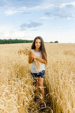 World food crisis. Deficit of grain in the world markets. A girl stands in a wheat field and holds ears of wheat in her hands.